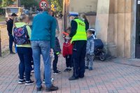 Rodzice i dzieci rozmawiają przed szkołą z policjantką