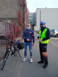 działania na rzecz bezpieczeństwa rowerzystów- policjant wręcza odblask rowerzyście