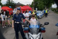 Policjantka obok policyjnego motocykla, na którym siedzi małe dziecko