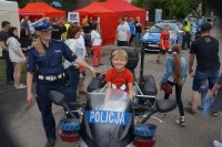 policjantka rozmawia z maluchami- jedno z dzieci siedzi na policyjnym motocyklu