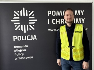 Zdjęcie przedstawia sierżanta sztabowego Błażeja Czerneckiego w kamizelce odblaskowej z napisem &quot;Policja&quot;.