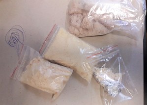 Zdjęcie przedstawia białą substancję w woreczkach, które zostały zabezpieczone przez policjantów.
